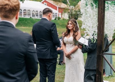 Outdoor wedding ceremony at Lupines & Lace wedding venue with floral arch and lush greenery.
