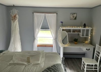 Wedding dress hanging by window with natural light at Lupines & Lace wedding venue.