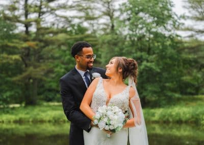 Elegant wedding couple at Lupines & Lace venue with lush greenery background.